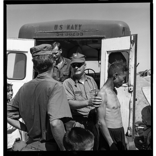 “How do you say, ‘where does it hurt?’” Doctor Hubbell asks PN3 Bruce Kohfield (back to camera) to translate.  Bruce was one of the few Seabees to have completed the Vietnamese language school back in Davisville. Bruce joins the MEDCAP field trips each week to help the doctors and corpsmen communicate with the villagers.